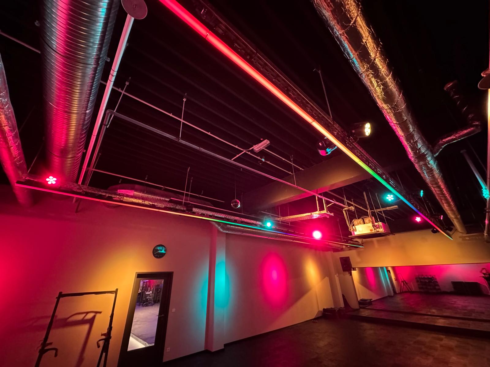 Showroom mit pinker Beleuchtung, Spiegelwand und Holzfußboden