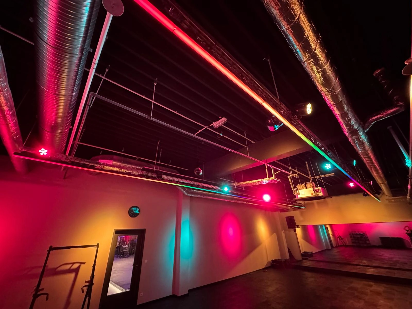 Showroom mit pinker Beleuchtung, Spiegelwand und Holzfußboden