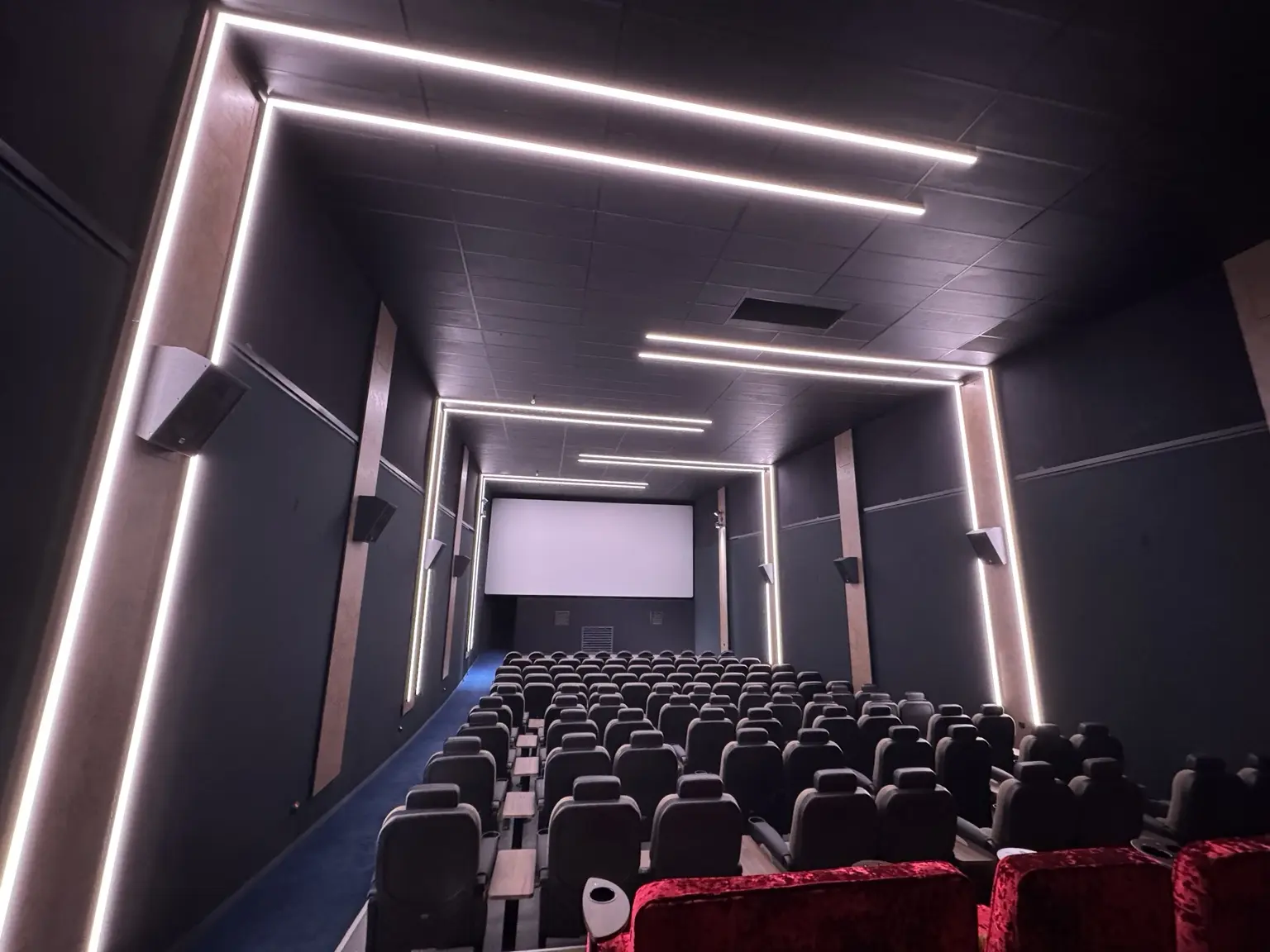 Kinosaal mit LED-Lichtlinien, Leinwand und stimmungsvoller Raumbeleuchtung